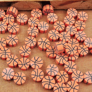 May include: A collection of orange and black basketball-themed round beads. The beads are made of a smooth, glossy material and have a raised black design.