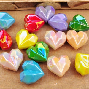 May include: Assortment of iridescent heart-shaped beads in various colors, including red, yellow, green, blue, and purple. The beads have a faceted, geometric design.