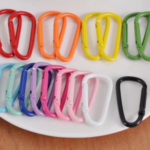May include: Assortment of colorful metal keychains in various colors, including blue, green, yellow, orange, pink, red, and black. The keychains are in the shape of a D-ring.