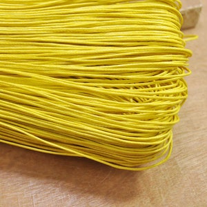 Puede incluir: Primer plano de un haz de cordón amarillo brillante. El cordón está enrollado apretado y parece estar hecho de una fibra natural.