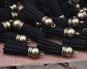 May include: A collection of black suede tassels with antique brass-colored caps and loops. The tassels are clustered together, showcasing their detailed design and texture. These decorative tassels are ideal for jewelry making or craft projects.