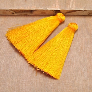 May include: Two bright yellow silk tassels with a long, flowing fringe. The tassels are made of soft, silky fabric and are perfect for adding a touch of elegance to any project.