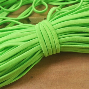 May include: A close-up of a bundle of bright green elastic cord. The cord is soft and flexible, and it is perfect for crafting projects.