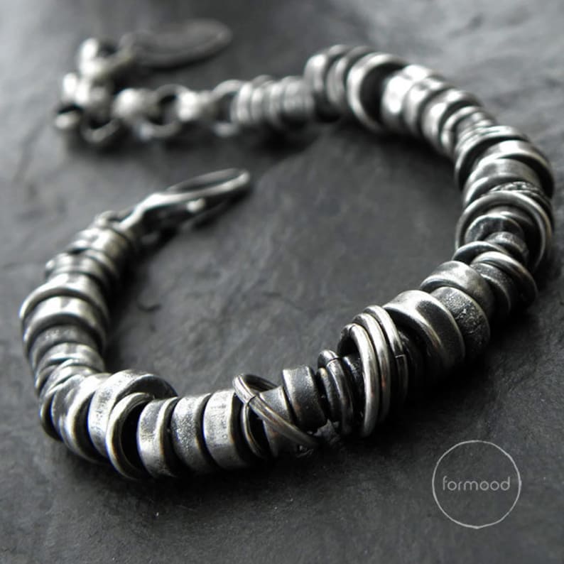 May include: A silver bracelet made of stacked, textured rings. The bracelet has a clasp closure.