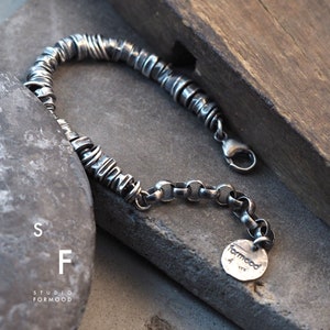 May include: A silver bracelet with a chain and a circular charm that says "formood".