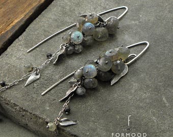 Peut inclure: Une paire de boucles d'oreilles pendantes en argent avec un groupe de pierres de labradorite grises et de petites feuilles argentées. Les boucles d'oreilles ont une chaîne délicate avec un petit charme en forme de cœur argenté.