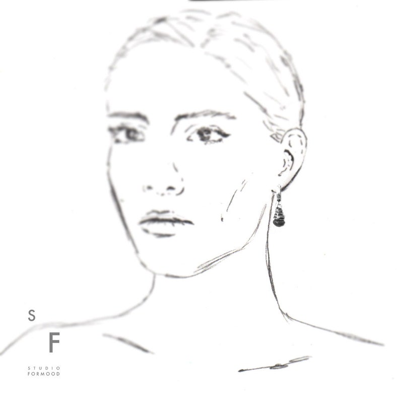 May include: A line drawing of a person wearing a pair of dangling earrings with a black stone at the bottom.