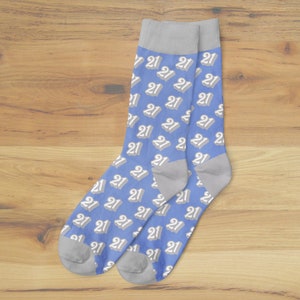May include: A pair of blue socks with a repeating pattern of the number "21" in white. The socks have gray heels, toes, and cuffs. These socks are a fun and festive accessory.