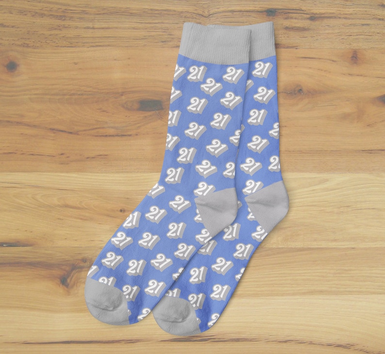 May include: A pair of blue socks with a repeating pattern of the number "21" in white. The socks have gray heels, toes, and cuffs. These socks are a fun and festive accessory.