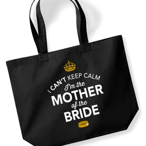 Puede incluir: Bolsa de tela negra con una corona dorada y el texto "I can't keep calm I'm the Mother of the Bride" en blanco. Un disco de hockey dorado se encuentra debajo del texto.