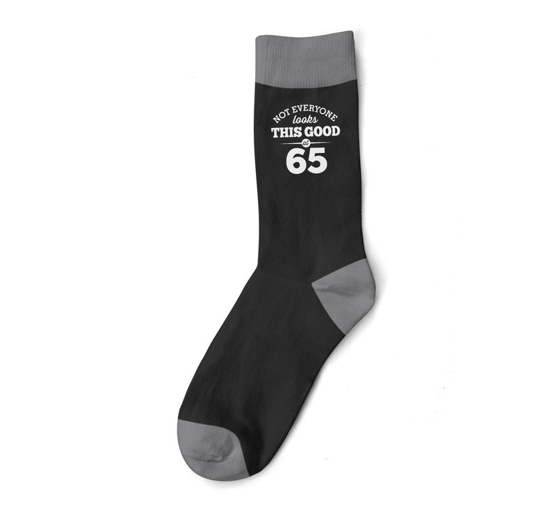 May include: Black and gray socks with white text that reads "Not everyone looks this good at 65".