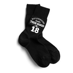 Puede incluir: Un par de calcetines negros con el texto blanco "NOT EVERYONE looks THIS GOOD at 18". Los calcetines se muestran sobre un fondo blanco.