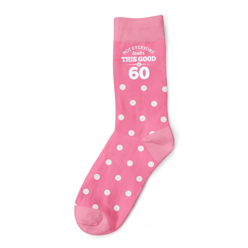 May include: Pink socks with white polka dots. The socks have the text "NOT EVERYONE looks THIS GOOD at 60" on them.