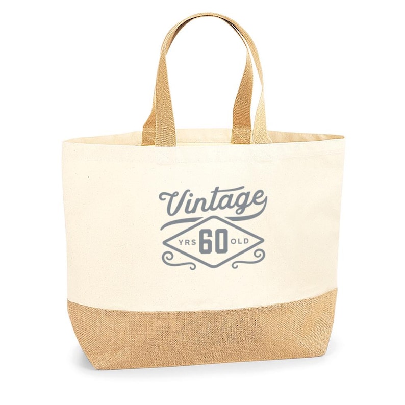 May include: A beige canvas tote bag with a jute bottom. The bag has a gray design that says "Vintage 60 YRS OLD" in a diamond shape.