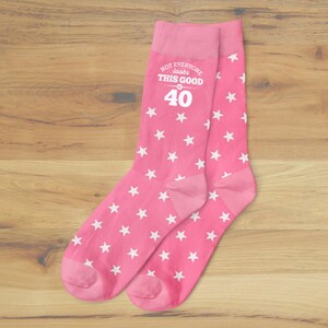 May include: Pink socks with white stars and the text "Not everyone looks this good at 40".