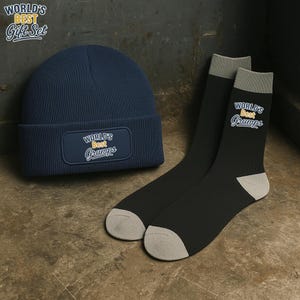 May include: A navy blue beanie and a pair of black socks with gray accents. The beanie has a patch that reads "World's Best Gramps". The socks also have the same text. The words "World's Best Gift Set" are in the upper left corner.