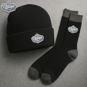 Pode incluir: Um gorro preto e um par de meias pretas com detalhes cinzentos. Ambos os itens apresentam um patch retangular com o texto "Vintage 1961" em um design clássico branco. O conjunto é um "Classic Gift Set".