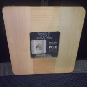 May include: A wooden picture frame with a label that reads "Finish It 3.5 x 3.5 in Memory Frame" and "DecorArt D.I.E. Die-Cut Memories". The frame is unfinished and ready to be painted or stained.