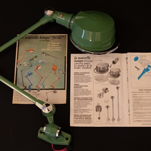 May include: A green metal desk lamp with a flexible arm and a round shade. The lamp is shown with its instruction manual, which includes the text "la nouvelle lampe "field"  con&ccedil;ue pour toutes les applications de la lampe standard".