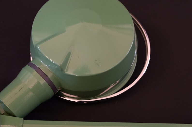 May include: A green metal lamp with a silver ring around the top. The lamp has a round, dome-shaped shade.