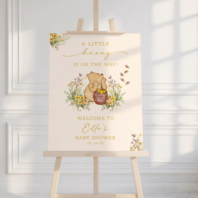 May include: A baby shower sign featuring a Winnie the Pooh illustration with the text "A Little Hunny Is On The Way!" and "Welcome to Ella's Baby Shower 03.14.2X". The sign is on a wooden easel, with floral accents.