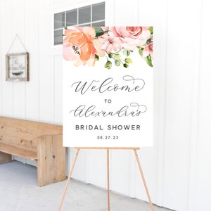 May include: A welcome sign for a bridal shower with a floral design in peach and pink tones. The sign reads "Welcome to Alexandra's Bridal Shower 06.27.23".