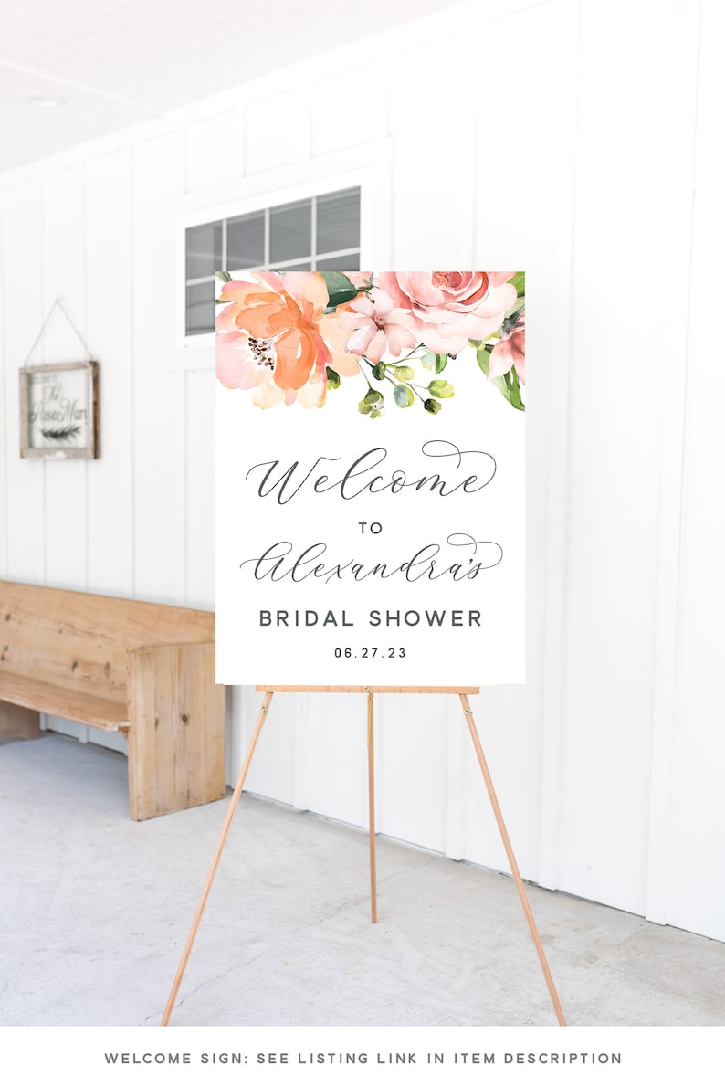 May include: A welcome sign for a bridal shower with a floral design in peach and pink tones. The sign reads "Welcome to Alexandra's Bridal Shower 06.27.23".