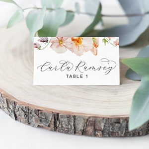 Peut inclure: Une carte de table blanche avec un motif floral compos&eacute; de fleurs roses et orange. Le texte "Carla Ramsey" et "Table 1" est imprim&eacute; en noir.