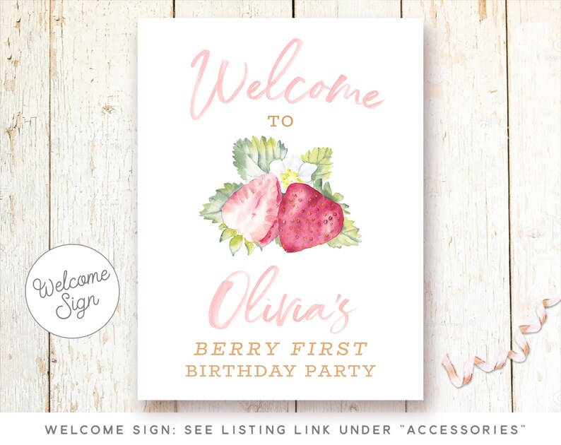 May include: Welcome sign for a first birthday party with a pink and white strawberry design. The sign says "Welcome to Olivia's Berry First Birthday Party".