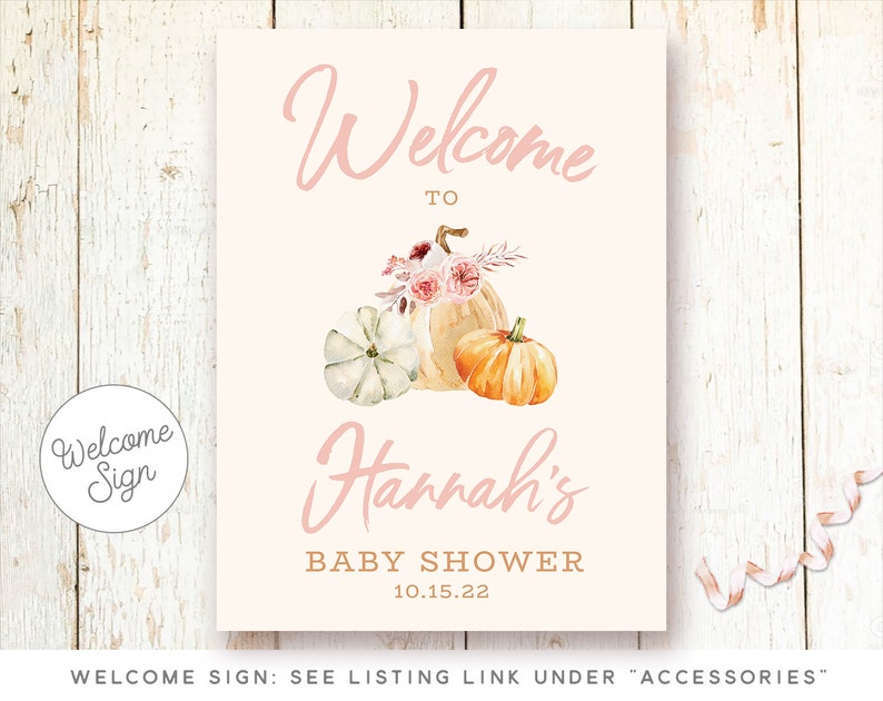 May include: Welcome sign for a baby shower with a pink background and a watercolor illustration of pumpkins and flowers. The text reads "Welcome to Hannah's Baby Shower 10.15.22".
