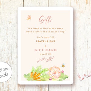 May include: A pink and white card with a floral design and the text "Gifts It's hard to live so far away when a little one is on the way! Let's help Jill TRAVEL LIGHT A GIFT CARD would fit justright!"