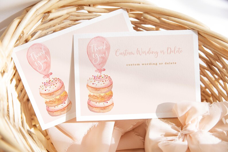 May include: Two pink cards with watercolor illustrations of donuts and balloons. One card says "Thank You!" and the other says "Custom Wording or Delete". The cards are in a woven basket with a pink ribbon.