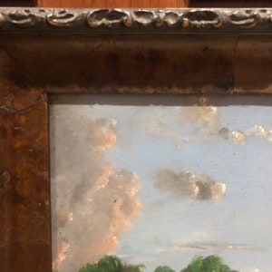 May include: A framed oil painting depicting a landscape scene with a blue sky, white clouds, and green trees in the foreground.