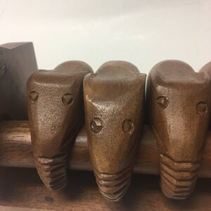 May include: A wooden rack with four carved wooden animal heads. The heads are brown and have a simple design. The rack is made of wood and has a natural finish.