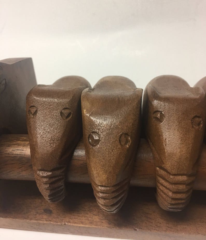 May include: A wooden rack with four carved wooden animal heads. The heads are brown and have a simple design. The rack is made of wood and has a natural finish.
