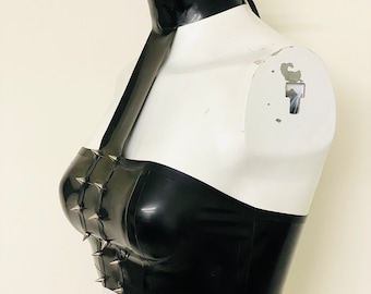 May include: A black latex halter top with a black choker and silver studs. The top is strapless and has a fitted bodice.