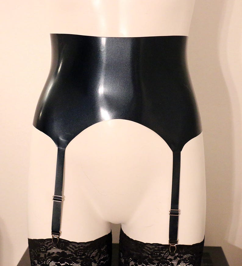 May include: A black latex garter belt with silver metal clasps and adjustable straps. The garter belt is on a white mannequin.