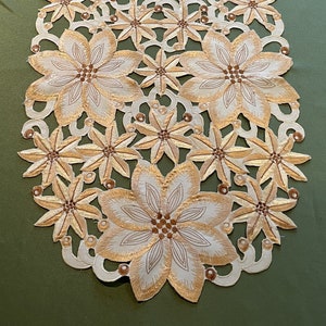 Peut inclure: Un chemin de table ovale blanc avec un motif floral délicat. Les fleurs sont brodées en fil d'or et ont une texture en relief. Le chemin de table est parfait pour ajouter une touche d'élégance à toute table.