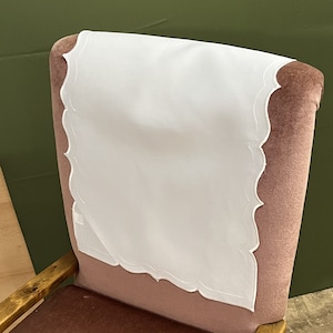 以下が含まれることがあります： ピンクのベルベットの椅子に、縁が波打った白い椅子のクッションが置かれています。椅子は木製のフレームです。