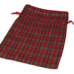 Può includere: Una borsa rossa a coulisse a quadri con un motivo ripetuto di linee rosse, verdi, gialle e blu. La borsa ha una chiusura con coulisse in nastro di raso rosso. La borsa è realizzata in tessuto morbido.