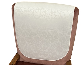Puede incluir: Funda blanca para el respaldo de la silla con un patrón floral. La funda está hecha de un tejido suave y texturizado y tiene una forma redondeada.