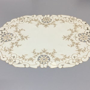 May include: White oval table runner with a delicate gold embroidered floral design.