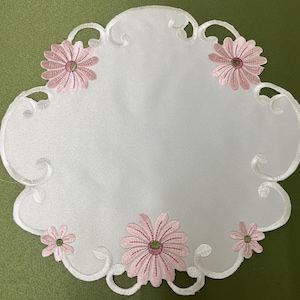 May include: White embroidered table runner with a scalloped edge and pink floral designs.