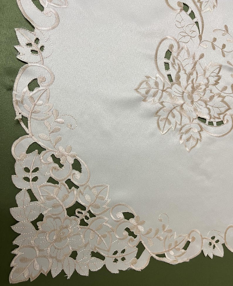 May include: White table runner with a delicate floral embroidery design in a cream color. The embroidery features intricate leaves and flowers, creating a classic and elegant look.