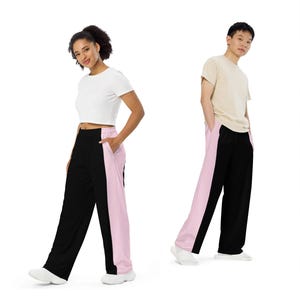 Unisex-Hose in schwarzer Farbe mit weiten Beinen, Seitentaschen und pink Seitenstreifen