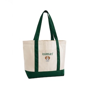 May include: Cream-colored canvas tote bag with dark green accents. The bag features a dark green base, trim, and handles. The word "RAMSAY" is embroidered in green above a cartoon beagle illustration.