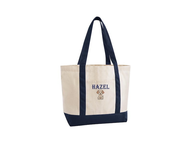 May include: Cream-colored tote bag with navy blue accents. The bag features navy blue handles and a navy blue bottom. The word "HAZEL" is embroidered in navy blue, along with a small puppy graphic.