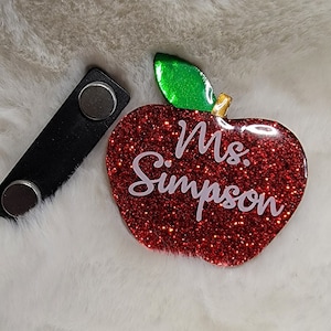 May include: Red glitter apple with a green leaf and gold stem. The apple has the text "Ms. Simpson" written in white.