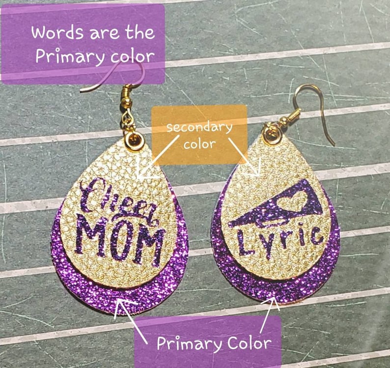 May include: Gold glitter earrings with purple glitter accents. One earring features the words "Cheer Mom" and the other earring features a cheerleader megaphone with the word "Lyric".