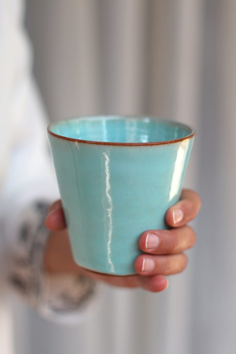 handmade pottery Turquoise tumbler in a hand